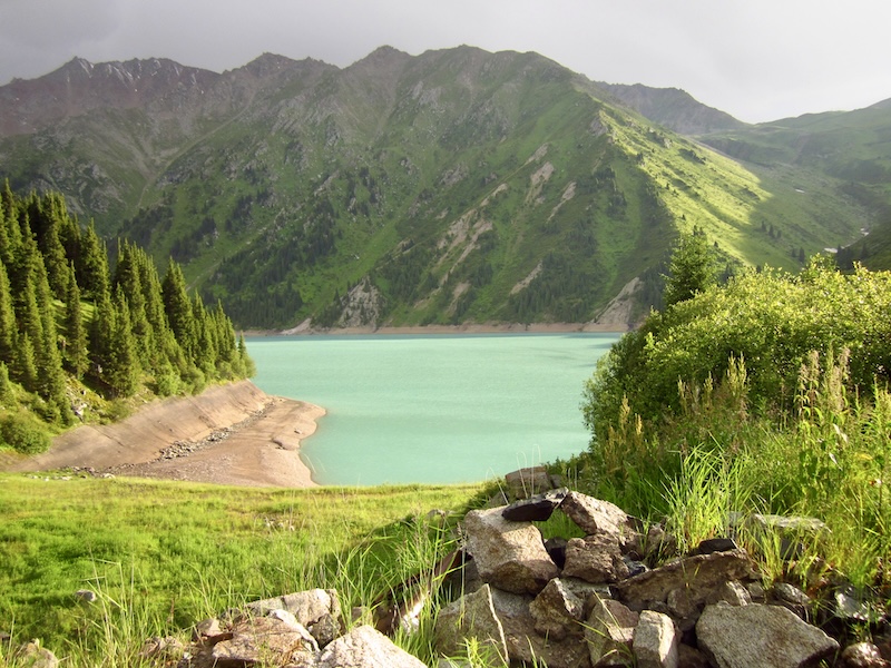 Turquoise waters of Big Almaty Lake surrounded by spruce forests and green mountain slopes, Northern Tien Shan