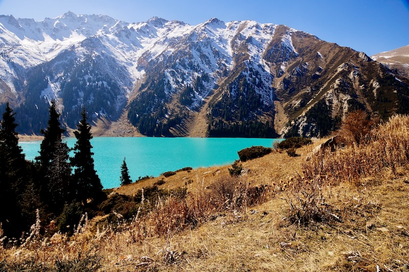 Big Almaty Lake with turquoise water and snow-covered mountain peaks in autumn, Northern Tien Shan