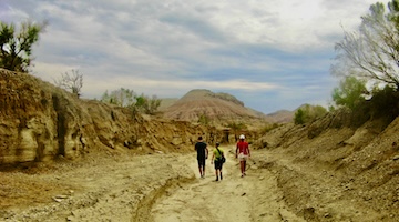 Three hikers walking through a dry canyon in the Aktau Mountains, Altyn Emel National Park